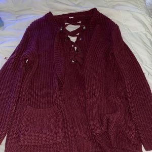 A long, thick Burgundy colored sweater with two pockets and an open back.